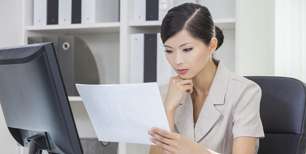 woman  at her desk reading a documen t