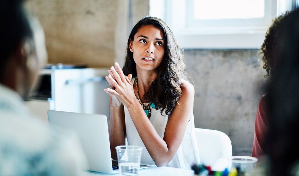 woman looking up from behind laptop