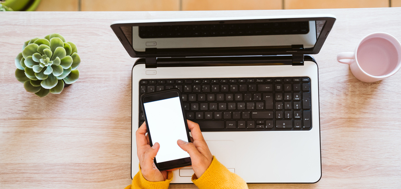 Top view of woman working at laptop while texting.