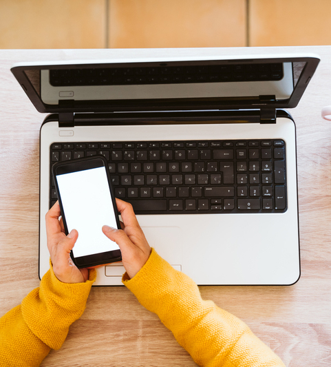 woman texting in front of laptop